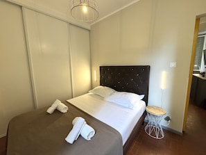 Una habitación de hotel con una cama, una mesita de noche, una lámpara y un espejo.