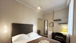 Una habitación de hotel con cama, escritorio, silla, espejo y lámpara.