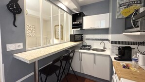 Una cocina compacta con microondas, tostadora, lavamanos y encimera de madera.