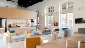 Un interno moderno con un angolo bar, diverse disposizioni di posti a sedere e ampie finestre.