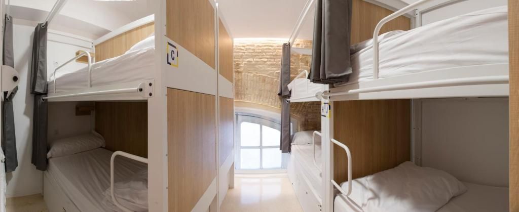 Een slaapkamer met een stapelbed, houten wand en een raam.