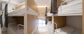 Une chambre avec un lit superposé, un mur en bois et une fenêtre.