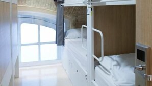 Una camera con un letto a castello, una finestra, una porta e un muro in pietra.