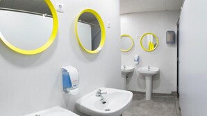 Un bagno moderno con due lavandini, uno specchio e un asciugamani ad aria.