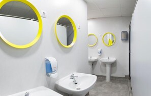 Une salle de bain moderne avec deux lavabos, un miroir et un sèche-mains.