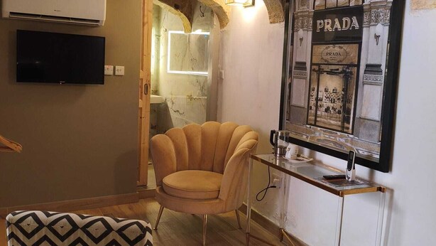 A room with a bed, a chair, a vanity with a mirror, and a television. - Wonderful Maltese Character 1-bedroom with AC in charming Ħal Tarxien (Ħal Tarxien)