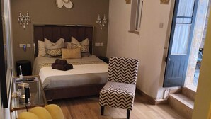 A bedroom with a bed, a chair, a bedside table, and a decorative wall piece. - Wonderful Maltese Character 1-bedroom with AC in charming Ħal Tarxien (Ħal Tarxien)