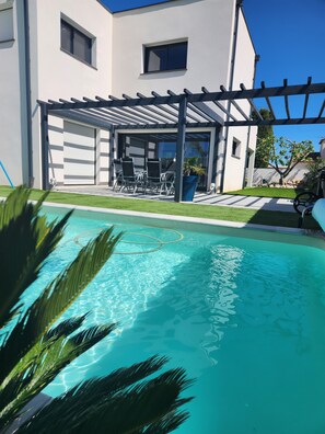 A swimming pool with a pergola and outdoor seating area. - Magnificent modern villa with private pool (Sérignan)