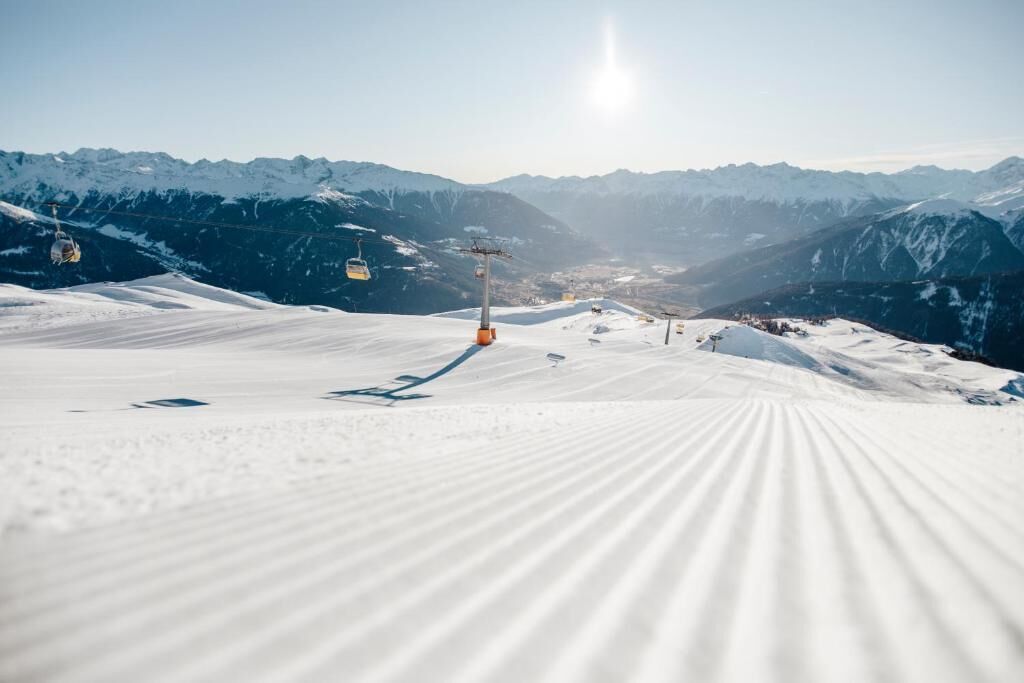 Pista de esquí cubierta de nieve con telesillas y montañas al fondo.