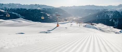 Pista de esquí cubierta de nieve con telesillas y montañas al fondo.
