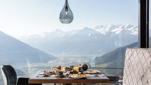 Mesa de jantar com itens de café da manhã e vista para as montanhas.