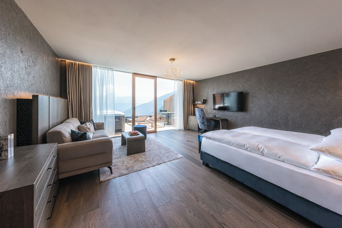 Ein modernes Hotelzimmer mit einem großen Bett, einer Couch, einem Schreibtisch und einem Fernseher.