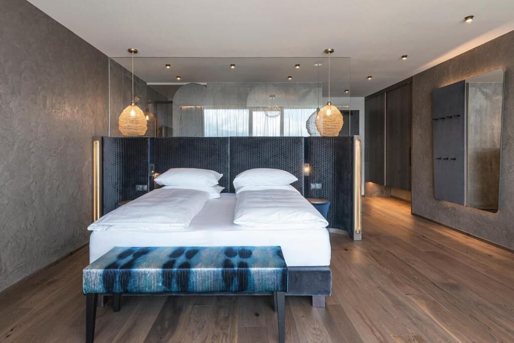 A modern bedroom with a large bed, bedside tables, and hanging pendant lights.