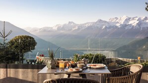 Mesa posta com itens de café da manhã e vista para montanhas cobertas de neve.