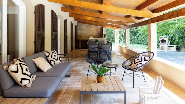 An open-plan living area with a sofa, chairs, a table, and a view of the outdoors.