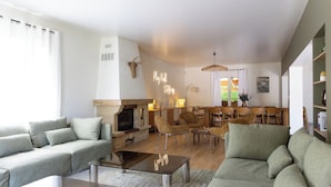A living room with a fireplace, sofa, coffee table, and dining area with chairs.