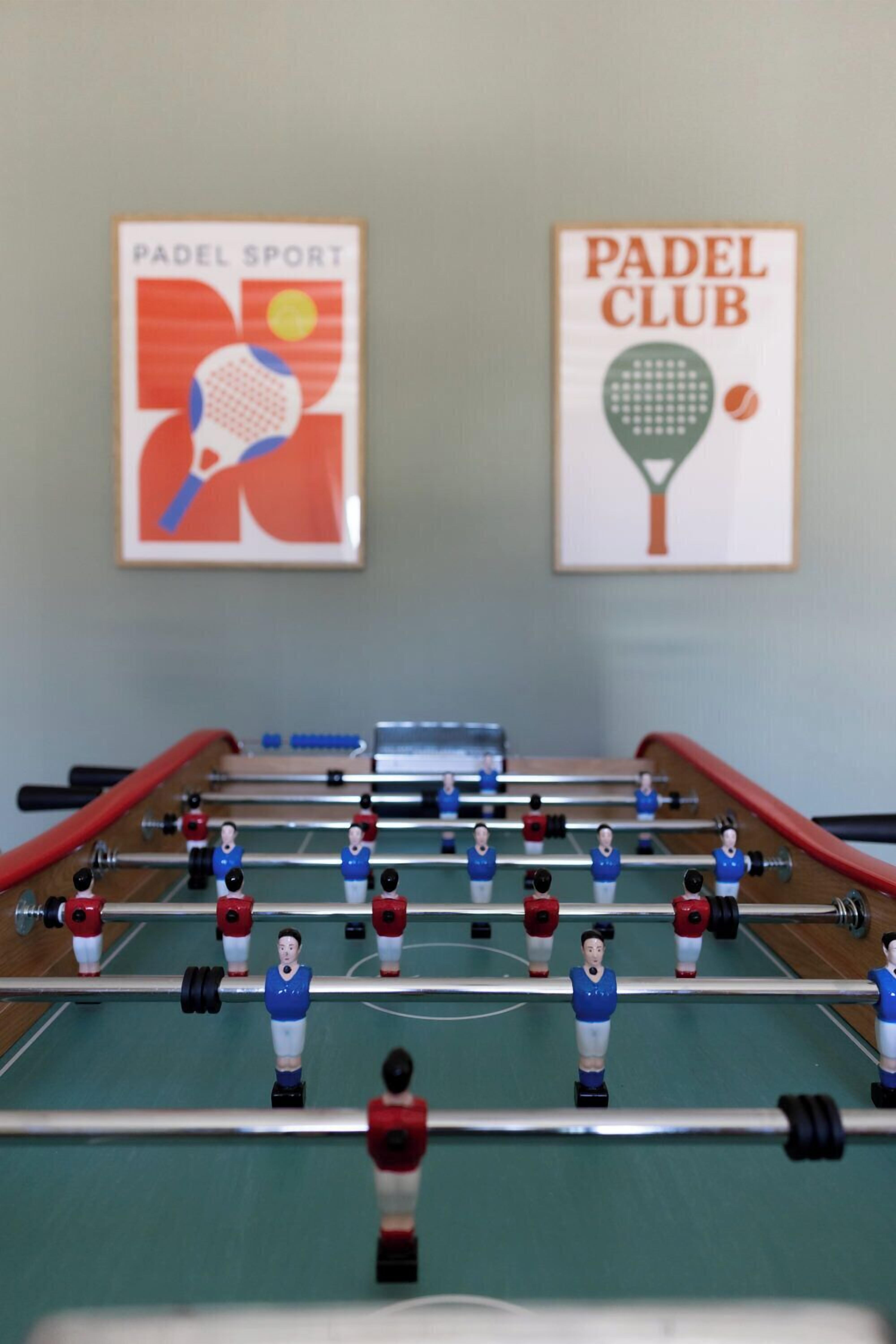 Una mesa de fútbol de mesa con dos carteles en la pared de fondo.