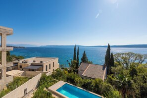 A pool with a view of the sea, a building with a terrace, and tall trees. - Well-kept vacation apartment with swimming pool - just a few steps from the beach (Crikvenica)