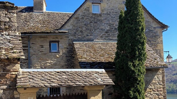 Un bâtiment en pierre à l’architecture traditionnelle, doté d’une grande porte en bois et d’une petite fenêtre.