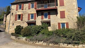 Un bâtiment en pierre doté de nombreuses fenêtres et de balcons, entouré de verdure.