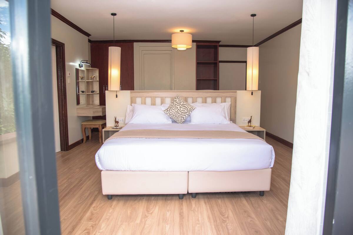 A bedroom with a large bed, bedside tables, a nightstand, a wardrobe, and a mirror.
