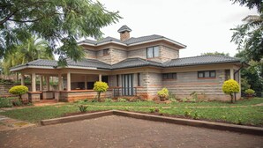 A two-story house with a covered porch, stone exterior, and a landscaped front yard. - Mt. Kenya View Villa 5BR Ensuite Guest Wing (Nyeri)