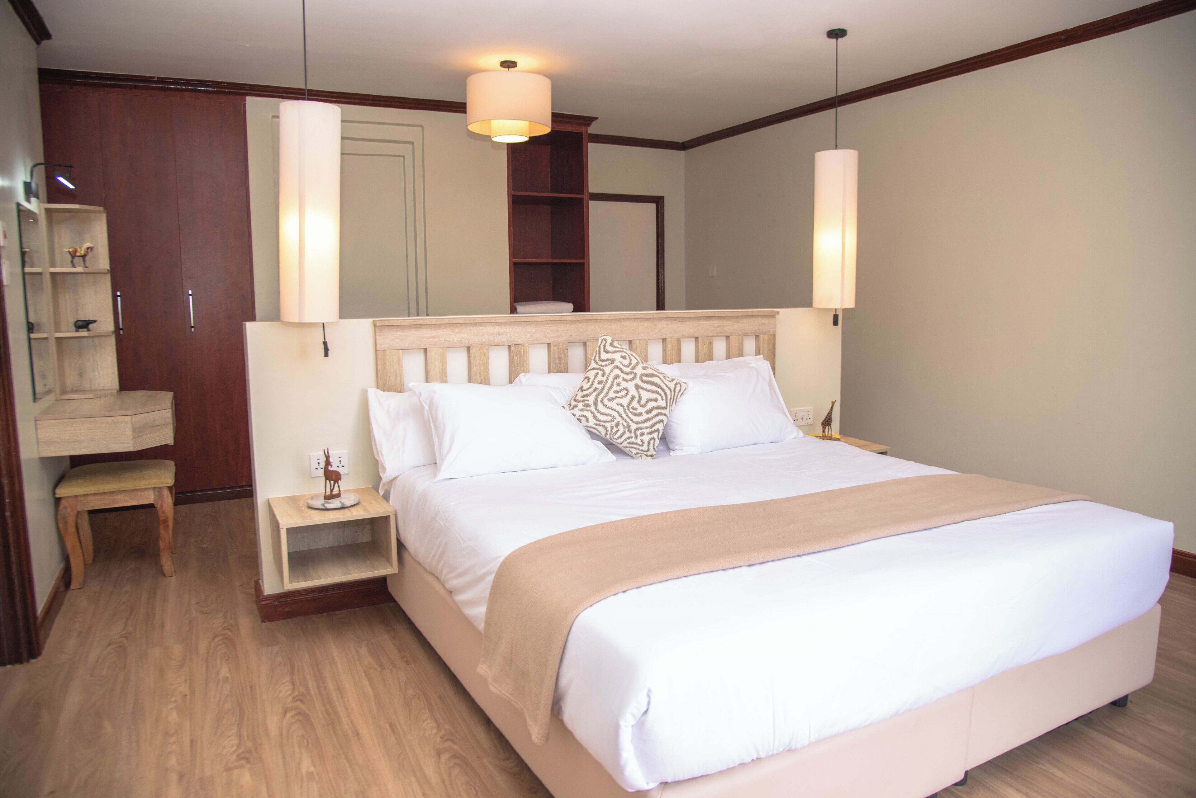 A neatly made bed with a wooden headboard, a bedside table with a lamp, and a small bench.