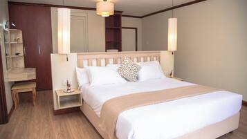 A neatly made bed with a wooden headboard, a bedside table with a lamp, and a small bench.