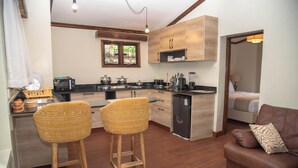 A compact kitchen with modern appliances, a dining area with two chairs, and a living room with a sofa. - Mt. Kenya View Villa 5BR Ensuite Guest Wing (Nyeri)