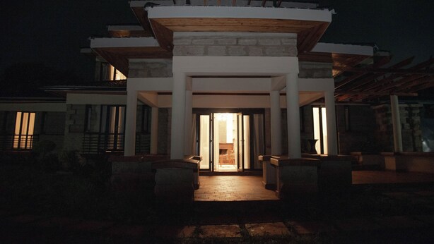A modern building with a stone facade, a wooden deck, and a well-lit entrance. - Mt. Kenya View Villa 5BR Ensuite Guest Wing (Nyeri)