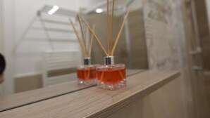 Deux bouteilles carrées en verre, avec des bâtonnets en bois, posées sur une surface en bois.