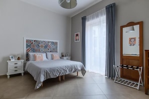 A bedroom with a bed, a nightstand, a dresser, a mirror, and a window with curtains. - Tinellari Rooms (Naples)