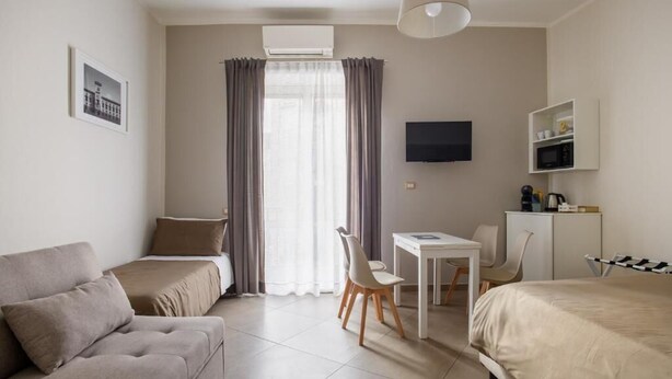 Une chambre d’hôtel comprenant un lit, un canapé, un bureau, une chaise, une télévision et une fenêtre avec des rideaux.