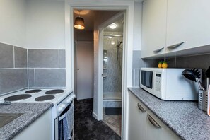 A compact kitchen with a stove, microwave, and granite countertops. - St Andrew's by Guestz (Lytham)
