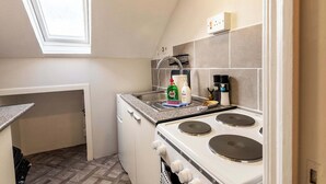 A compact kitchen with a stove, sink, and a window. - St Andrew's by Guestz (Lytham)