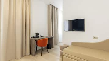 Une chambre d’hôtel moderne équipée d’un bureau, d’une chaise, d’un canapé et d’un téléviseur à écran plat fixé au mur.