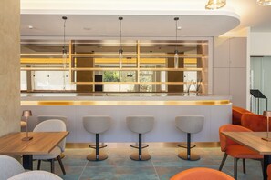 A modern bar area with a curved counter, bar stools, and pendant lighting.