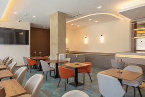 Un intérieur de restaurant moderne, avec plusieurs tables et chaises, un bar et une grande colonne.