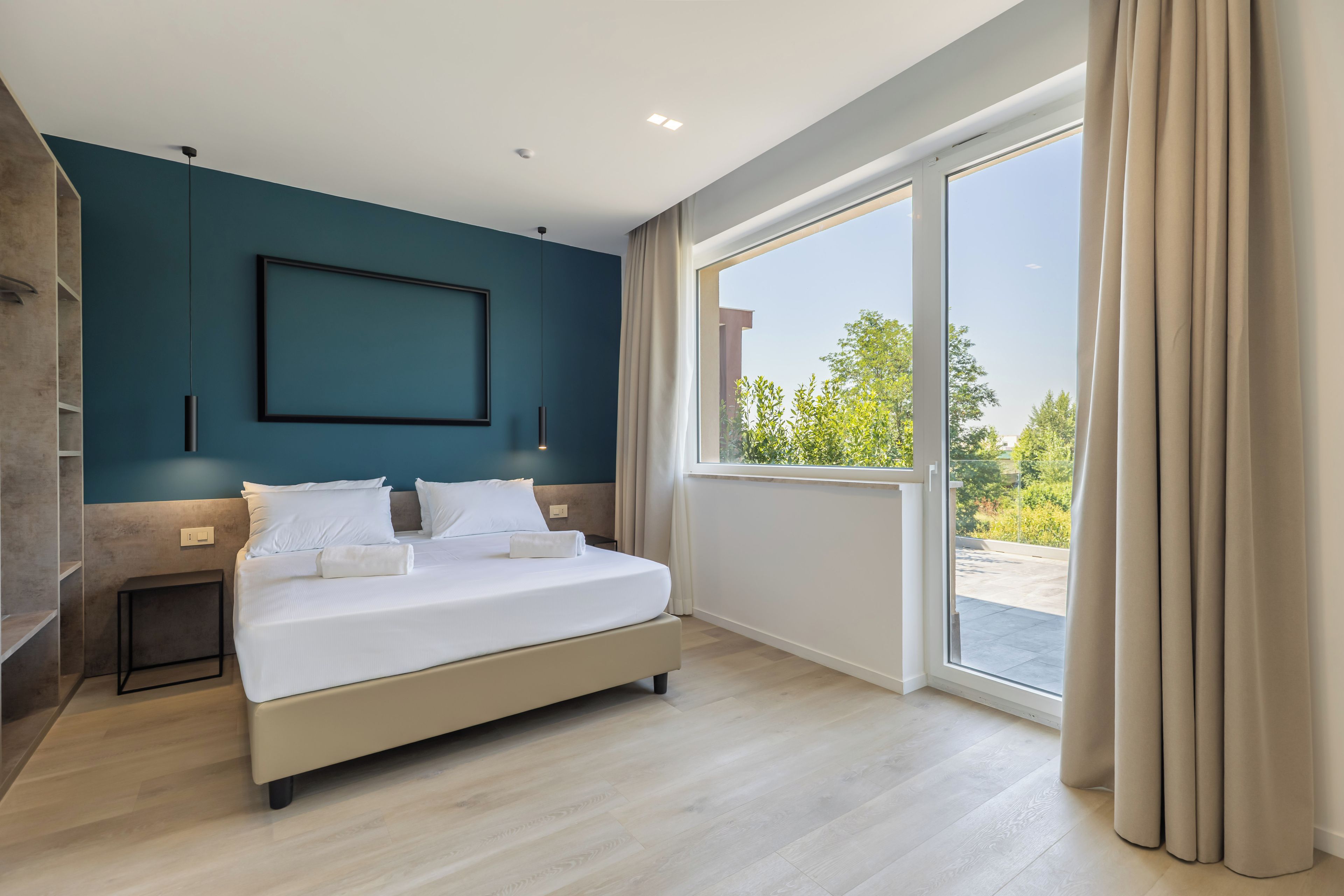 Ein modernes Schlafzimmer mit einem großen Bett, Blick ins Grüne und einem minimalistischen Design.