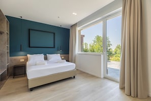 A modern bedroom with a large bed, a view of greenery outside, and a minimalist design. - MU21 Hotel (Naples)