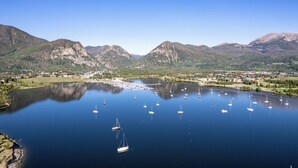Um lago com barcos, rodeado por montanhas e uma vila.