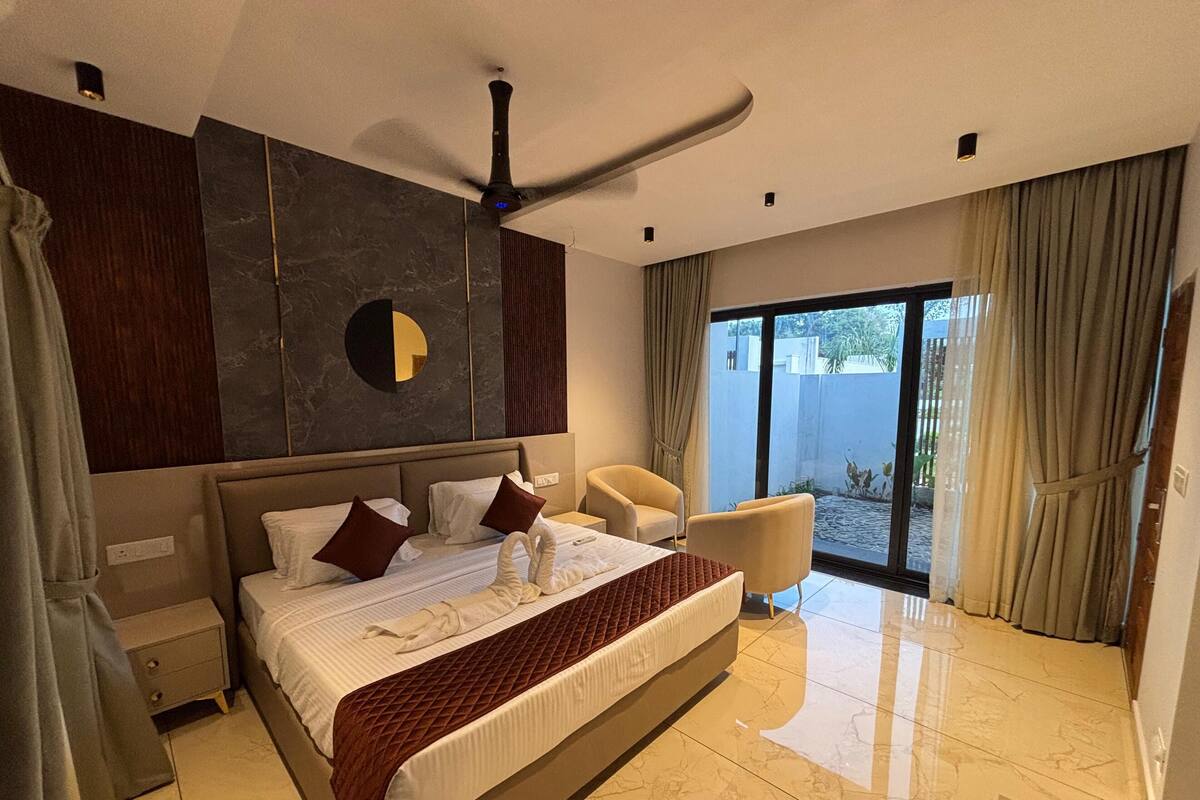 Une chambre d’hôtel moderne dotée d’un grand lit, d’un ventilateur de plafond, d’un coin salon et donnant sur l’extérieur grâce à une porte vitrée.