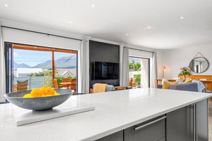 Una cocina moderna con una isla grande, un comedor con sillas y un televisor montado en la pared.