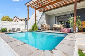 A swimming pool with a wooden pergola overhead, surrounded by stone tiles. - Cape Winelands Mountain View Getaway (Stellenbosch)