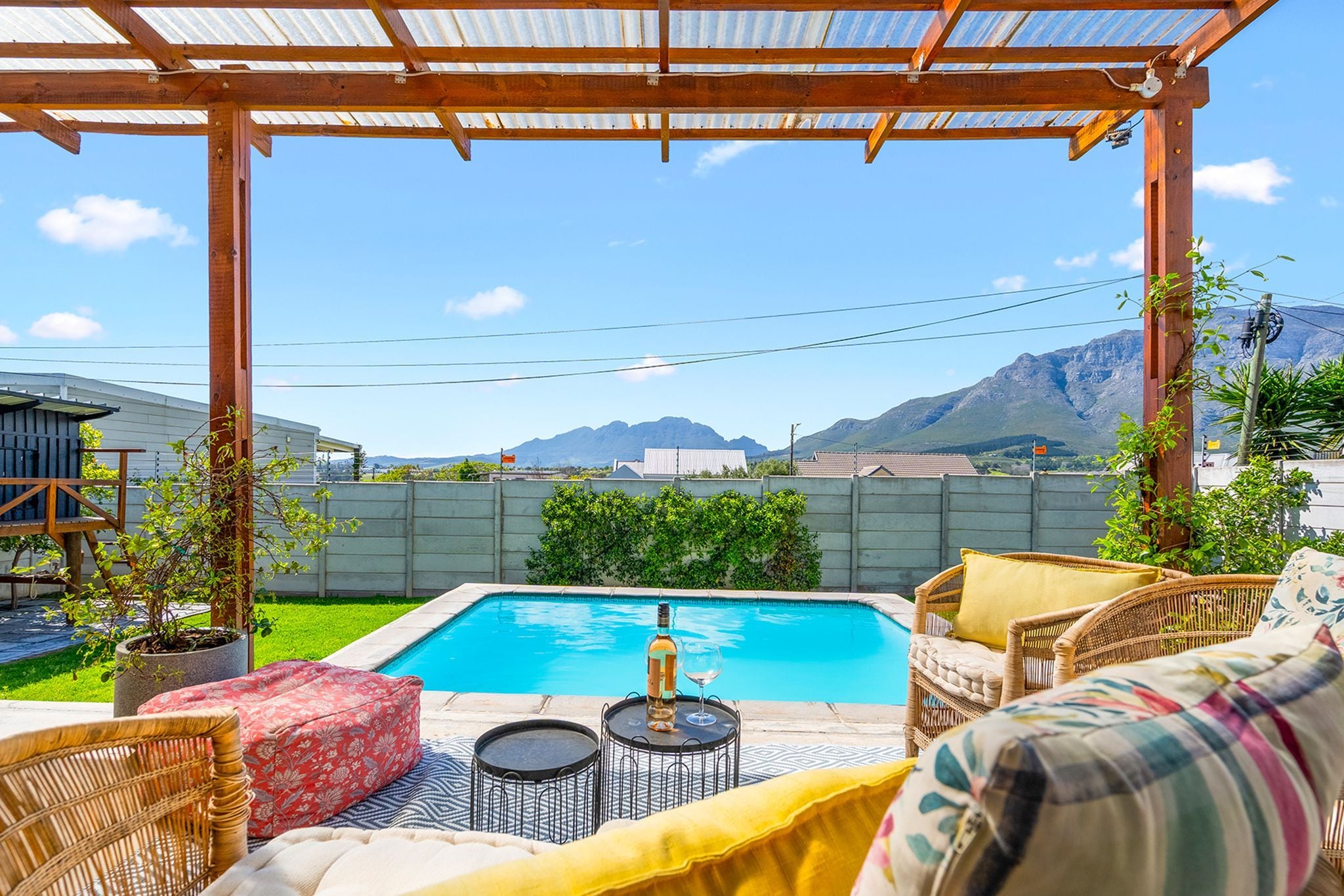 A pool area with a pergola, outdoor furniture, and a view of mountains.