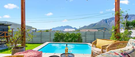 A pool area with a pergola, outdoor furniture, and a view of mountains.