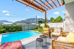 A pool area with wicker furniture and a pergola. - Cape Winelands Mountain View Getaway (Stellenbosch)