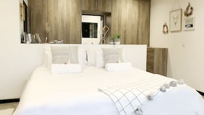 Een slaapkamer met een groot bed, een houten garderobe en een klein raam.