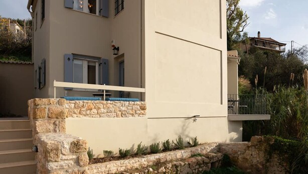 Ein modernes Haus mit Steintreppe, einem Balkon und einem Pool.