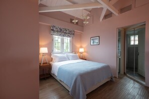 A bedroom with a bed, two bedside lamps, a window with a valance, a door, and a shower area. - Sirocco Maisonette Kyparissia Old Town Collection (Trifylia)